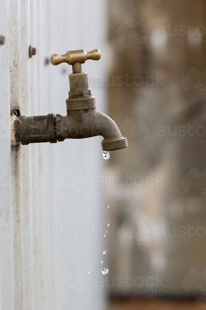 Dripping tap on outside wall of shed - Australian Stock Image