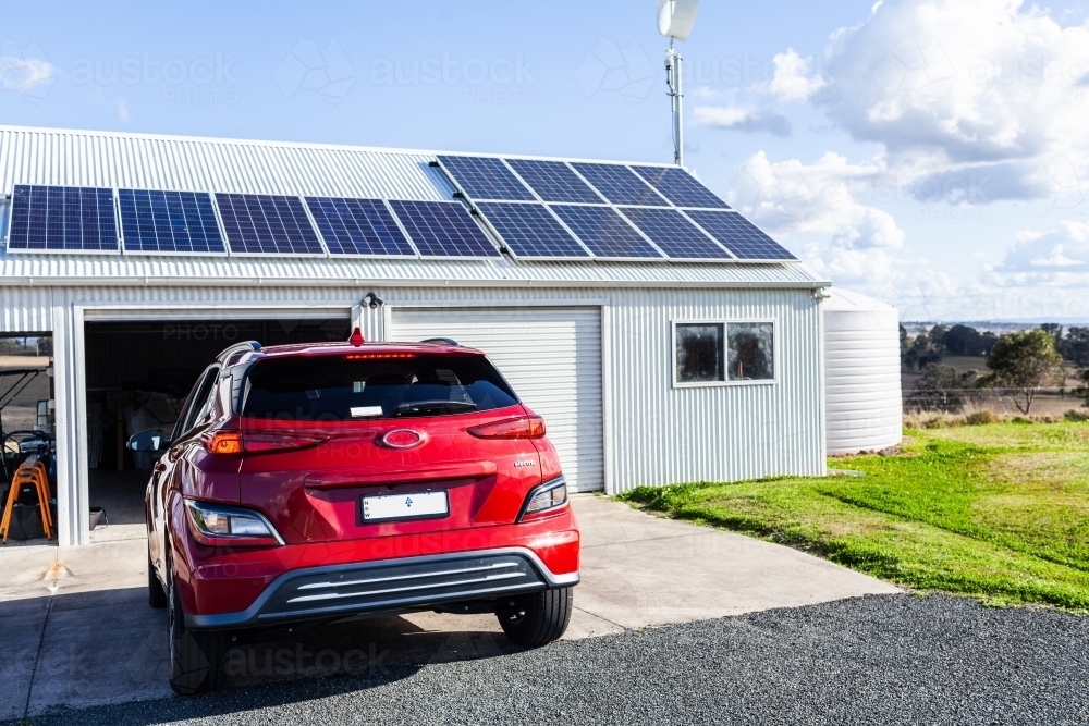 Image of Driving electric vehicle car into solar and wind powered shed