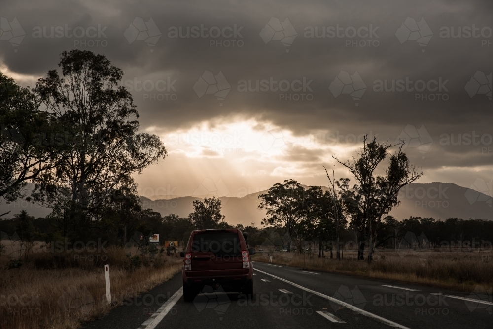 driving up the Bruce Highway in Central Queensland towards the sun peeking through clouds - Australian Stock Image