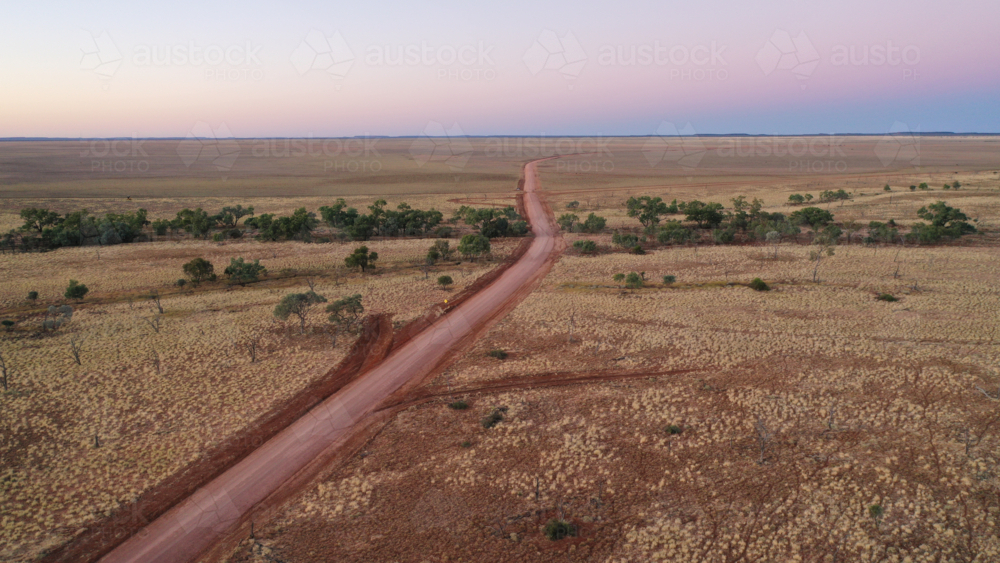 Drone shot of a dirt road going through creek and plain - Australian Stock Image