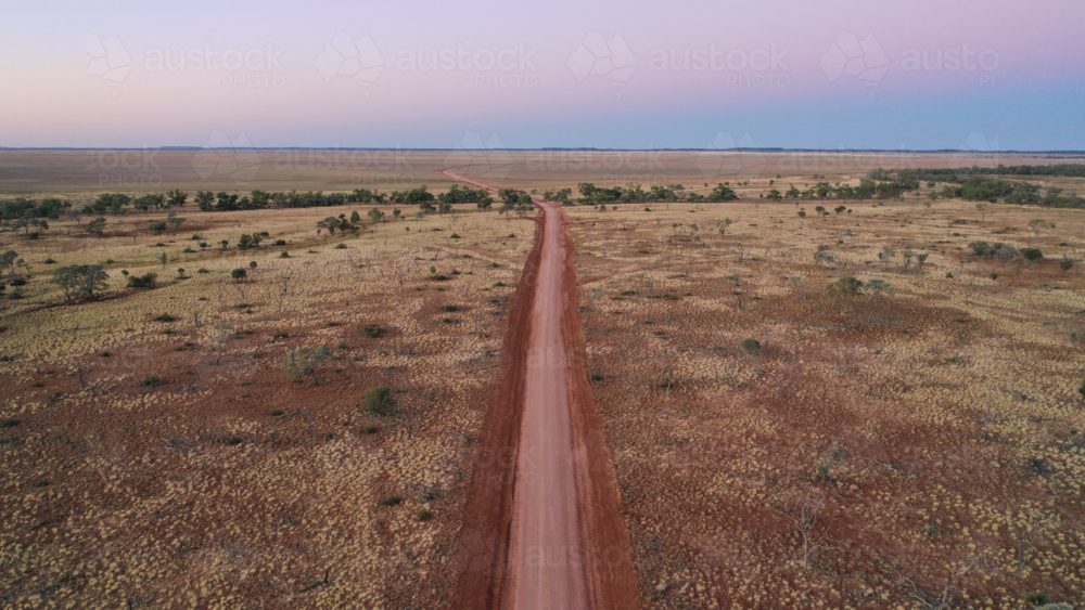 Drone shot of a dirt road going through creek and plain - Australian Stock Image