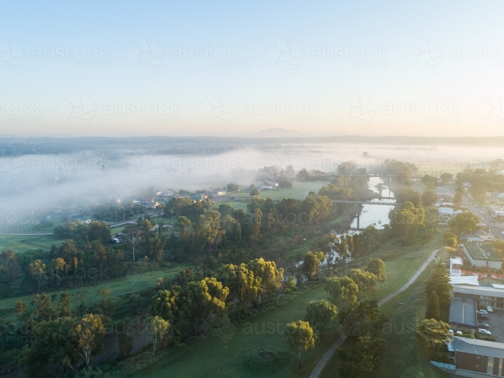 First Daylight Image of Drone view of first daylight on treetops with river and mist ...