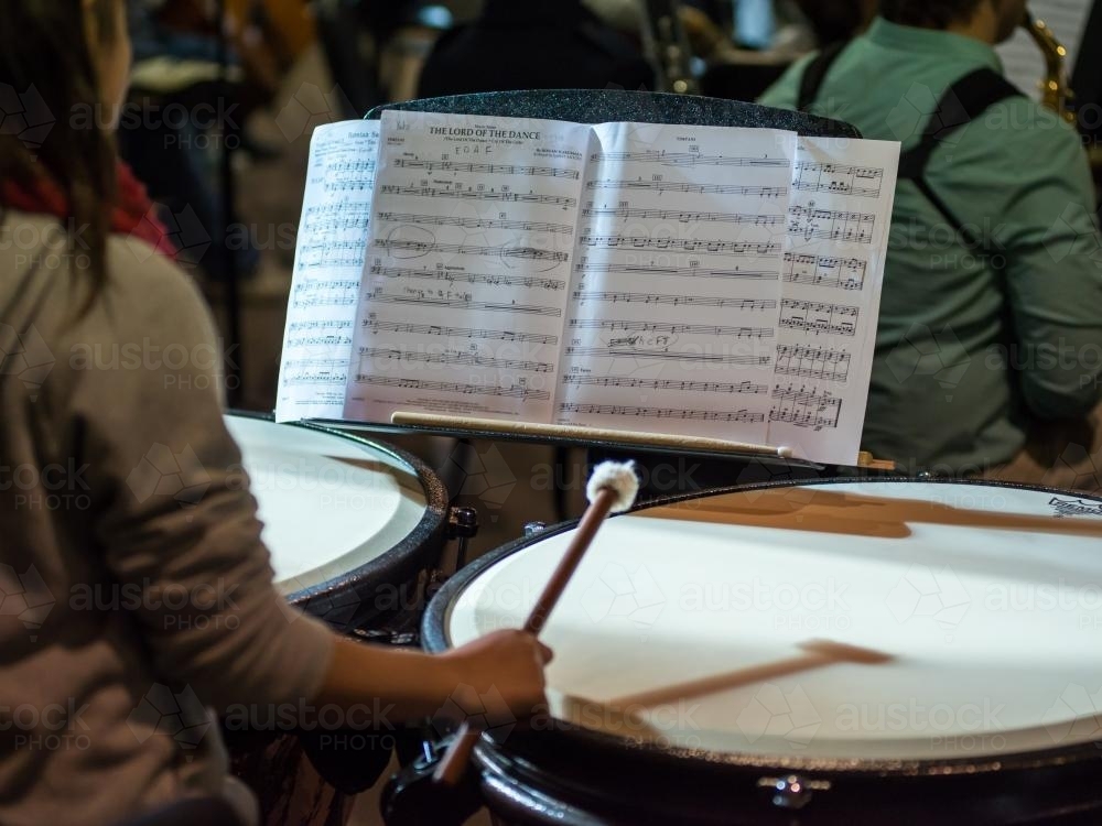Drummer in an orchestra reading the music score - Australian Stock Image