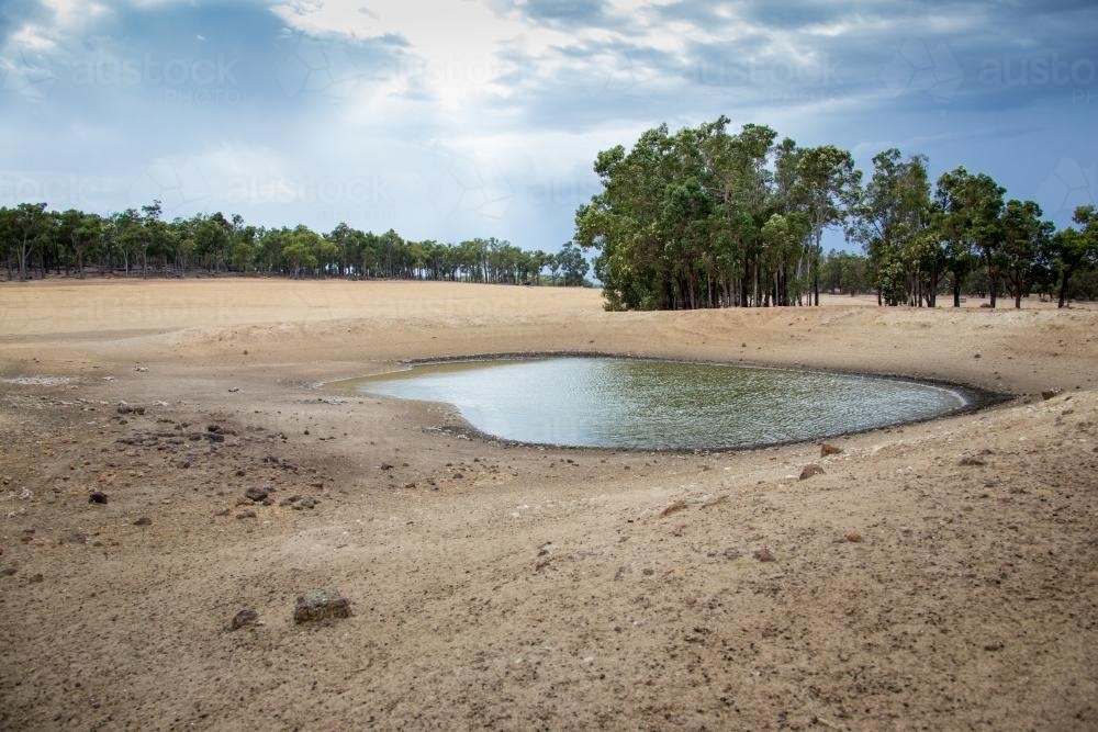 Dry farmland with small amount of water in dam - Australian Stock Image