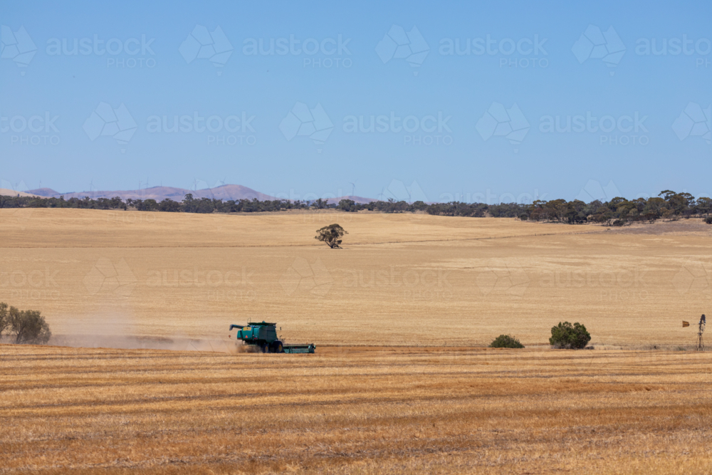 Dry-land farming machinery harvesting crop in farm paddock - Australian Stock Image
