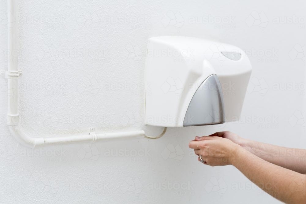 Drying hands at an outdoor public hand dryer. - Australian Stock Image