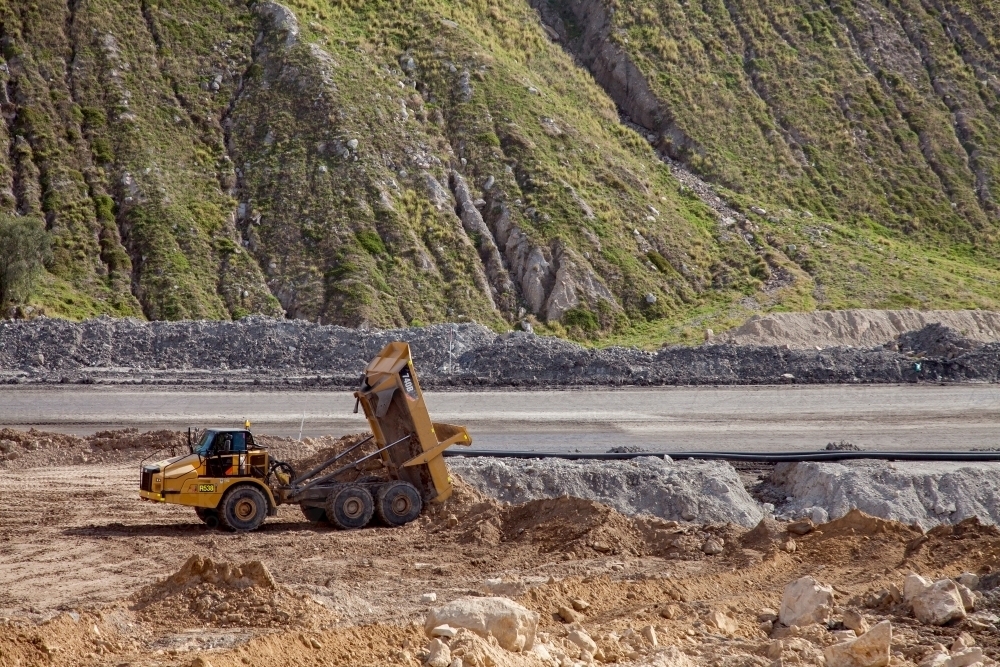 Dump truck moving dirt beside open cut mine - Australian Stock Image