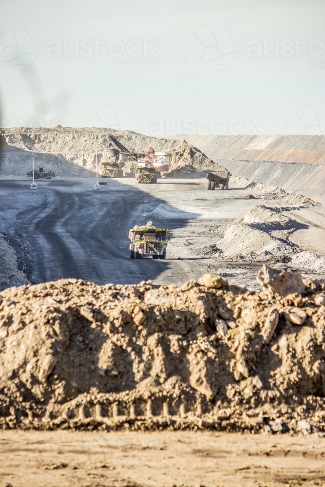 Dump trucks filling up with overburden and carting it through open cut coal mine - Australian Stock Image
