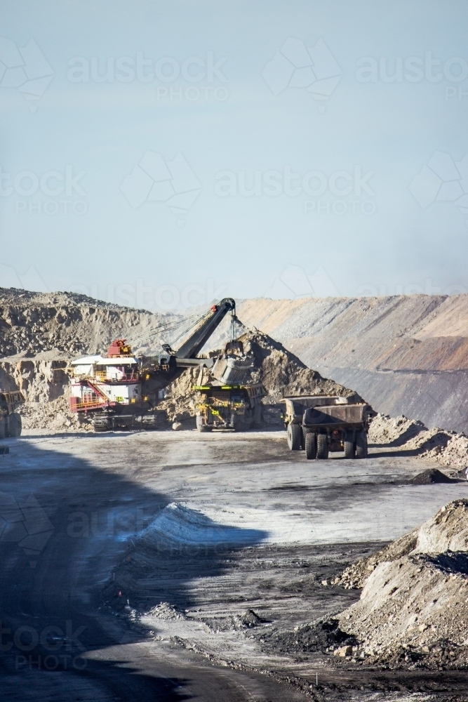 Dump trucks filling up with overburden and carting it through open cut coal mine - Australian Stock Image