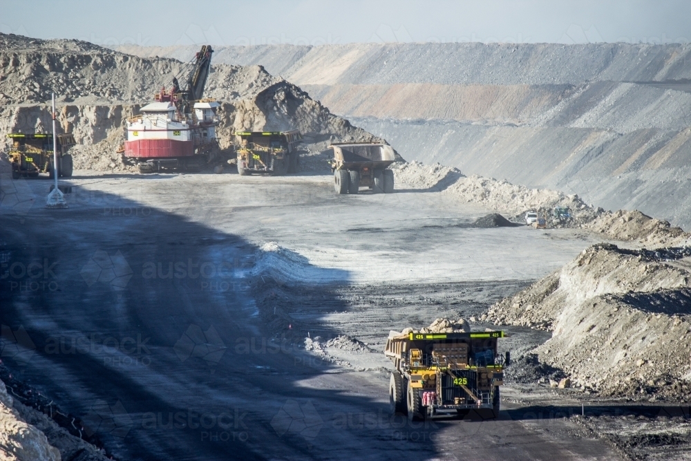 Dump trucks filling up with overburden and carting it through open cut coal mine - Australian Stock Image