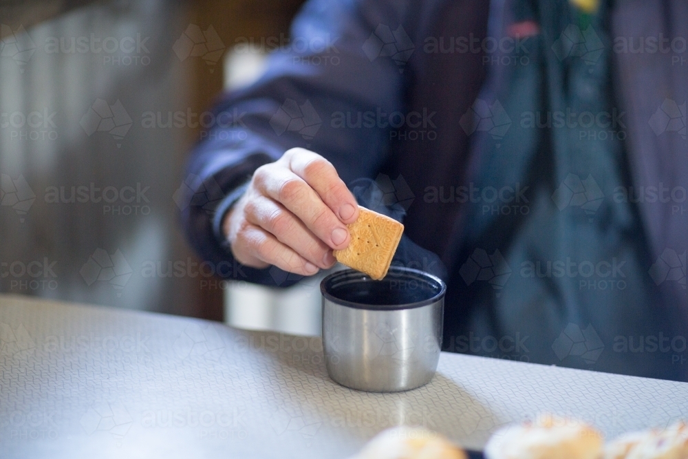 Dunking biscuit in a cup of tea - Australian Stock Image