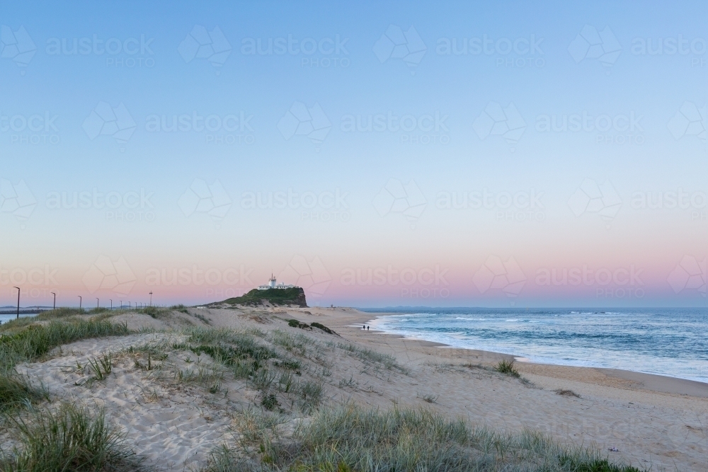 Dusk light over Newcastle headland at Nobbys Beach with lighthouse  - Australian Stock Image