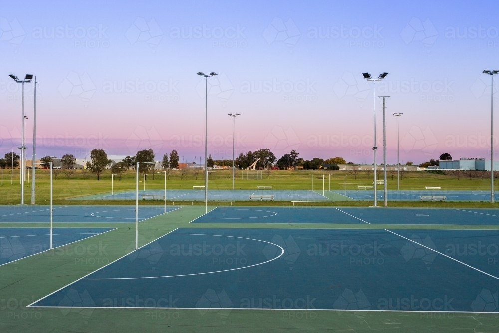Dusk sky behind empty netball courts in sports park - Australian Stock Image