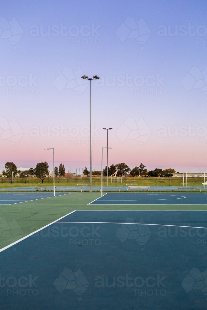 Dusk sky behind empty netball courts in sports park - Australian Stock Image