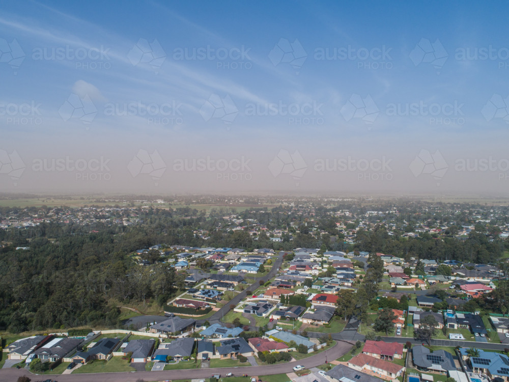 Dust storm haze on horizon over rooves of Australian town in bright sunlight - Australian Stock Image