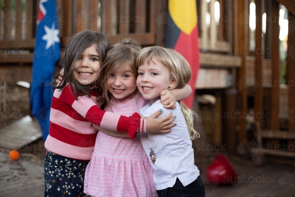 Early education, three girls hugging - Australian Stock Image
