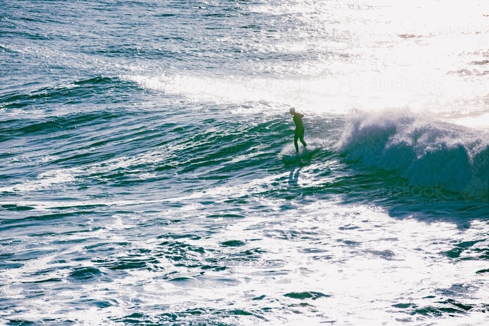 Early morning silhouetted surfer riding a wave - Australian Stock Image