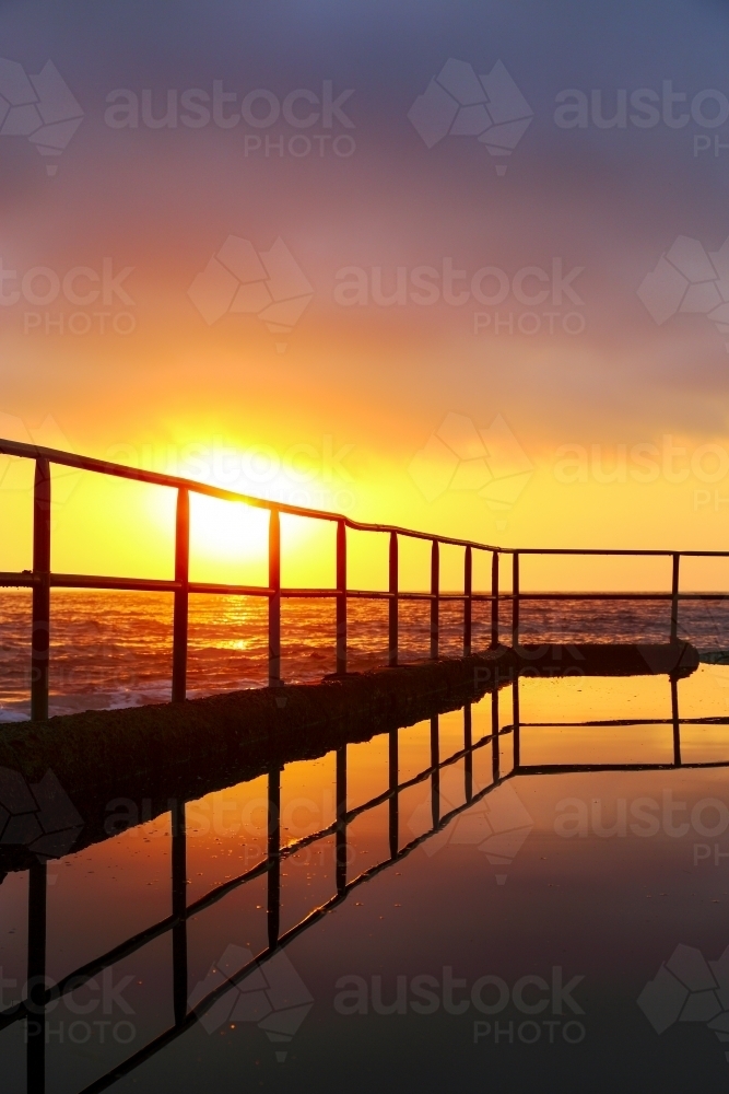 Early morning sunrise and reflections in the Wombarra Rock Pool on the Illawarra Coast, NSW - Australian Stock Image