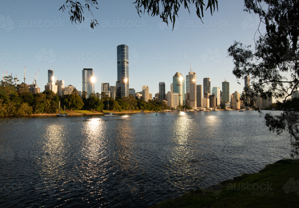 Early morning view across river to city with sunbursts and reflections - Australian Stock Image