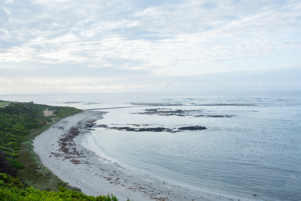 Edge of sandy beach with reef exposed and soft light - Australian Stock Image