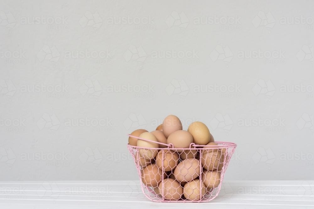 eggs in a pink wire basket - Australian Stock Image