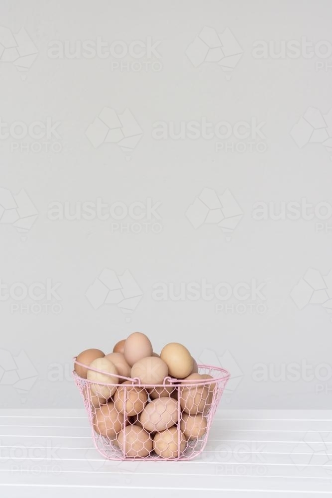 eggs in a pink wire basket - Australian Stock Image