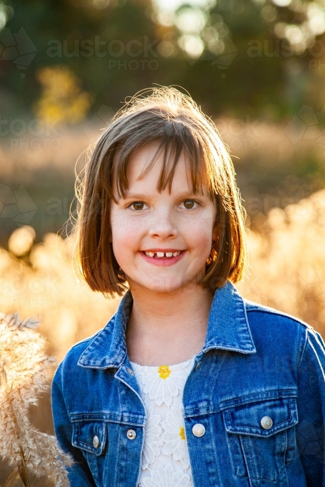 Eight year old girl outside backlit by golden sunset light - Australian Stock Image