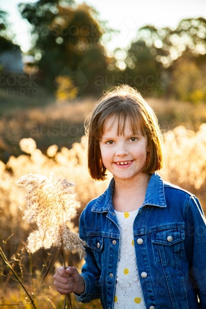 Eight year old girl outside backlit by golden sunset light - Australian Stock Image