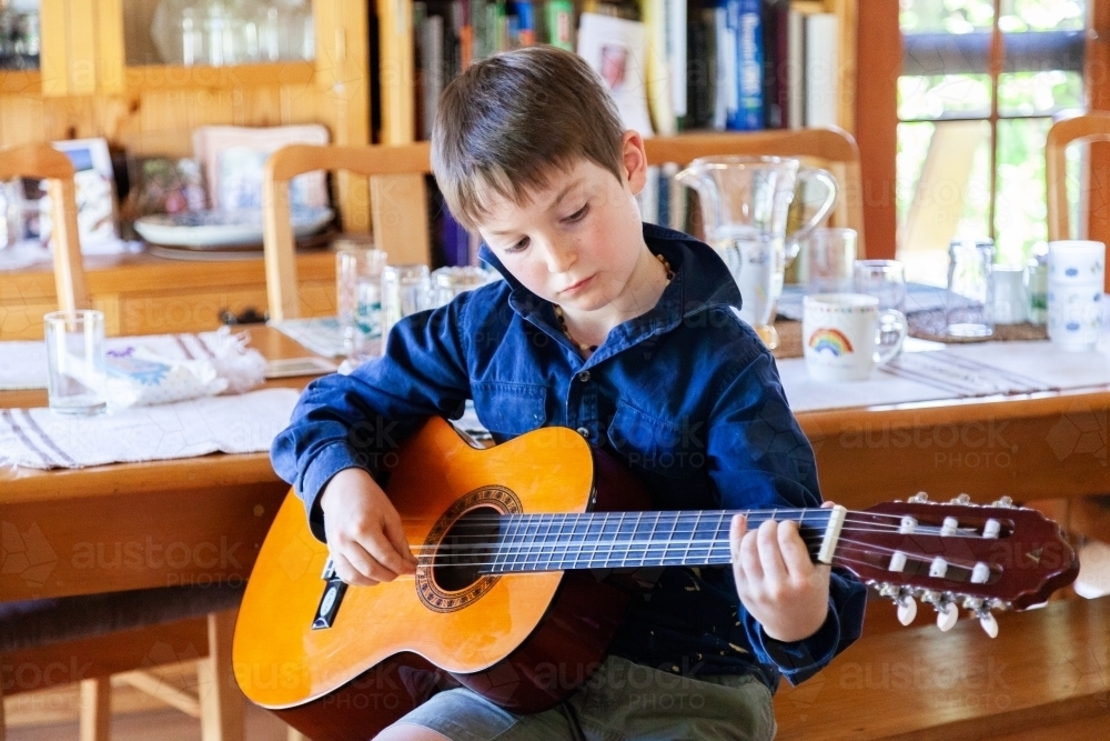 Eight year old guitar student playing his instrument - Australian Stock Image