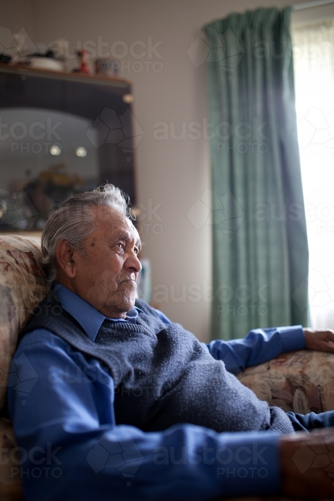 Elderly aboriginal man sitting in lounge chair - Australian Stock Image