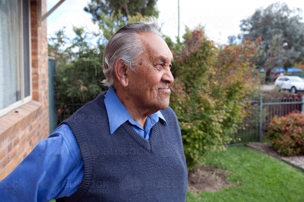 Elderly aboriginal man standing outside his house - Australian Stock Image