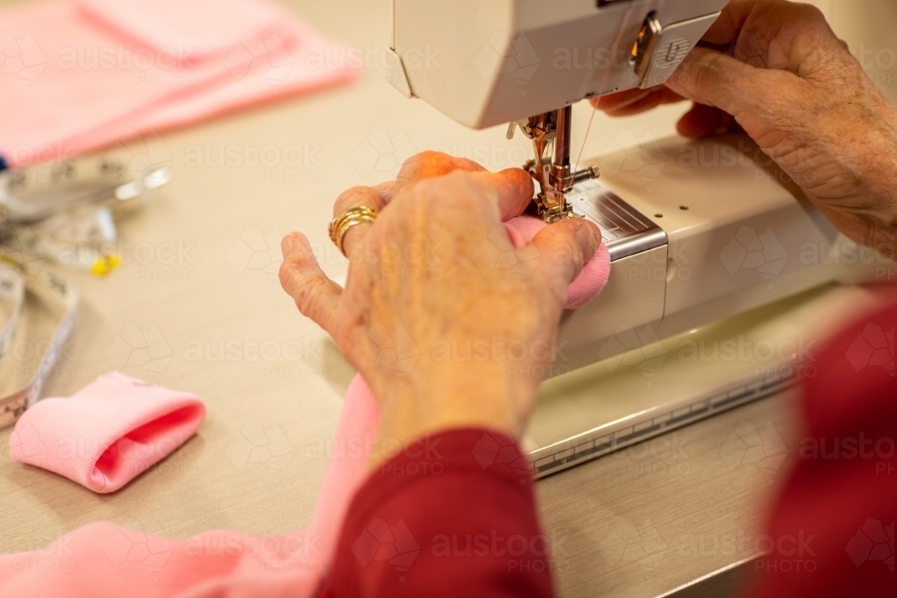 elderly hands operating sewing machine - Australian Stock Image
