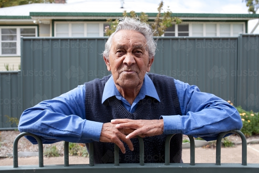 Elderly indigenous man  leaning on fence - Australian Stock Image