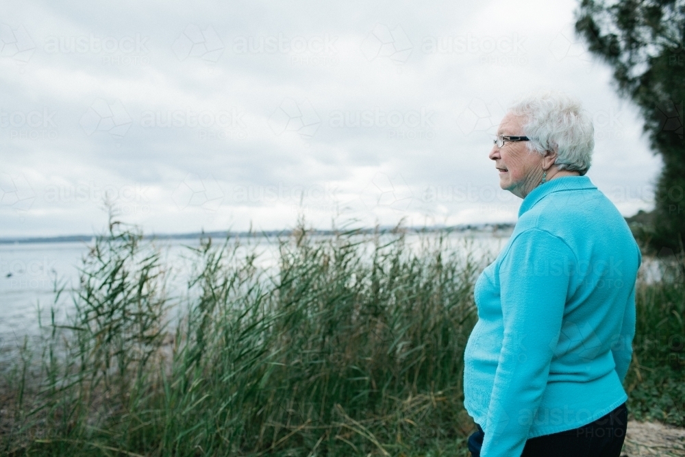 Elderly lady looking out towards a lake - Australian Stock Image