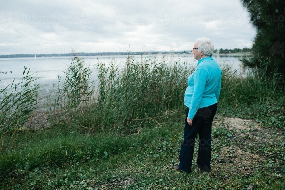 Elderly lady looking out towards a lake - Australian Stock Image