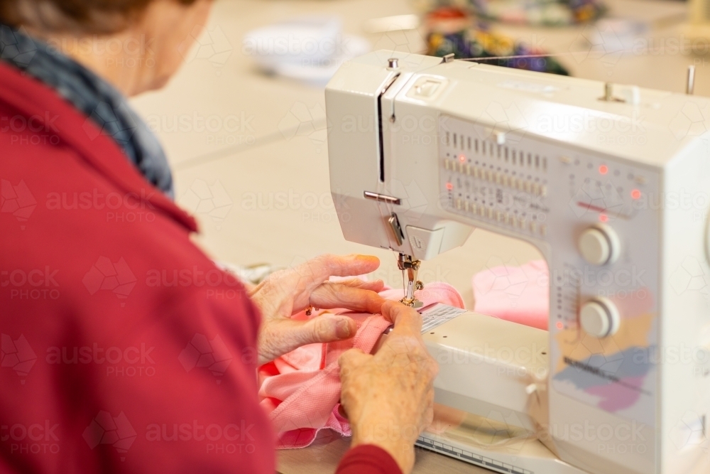 elderly lady sewing hem on garment with sewing machine - Australian Stock Image