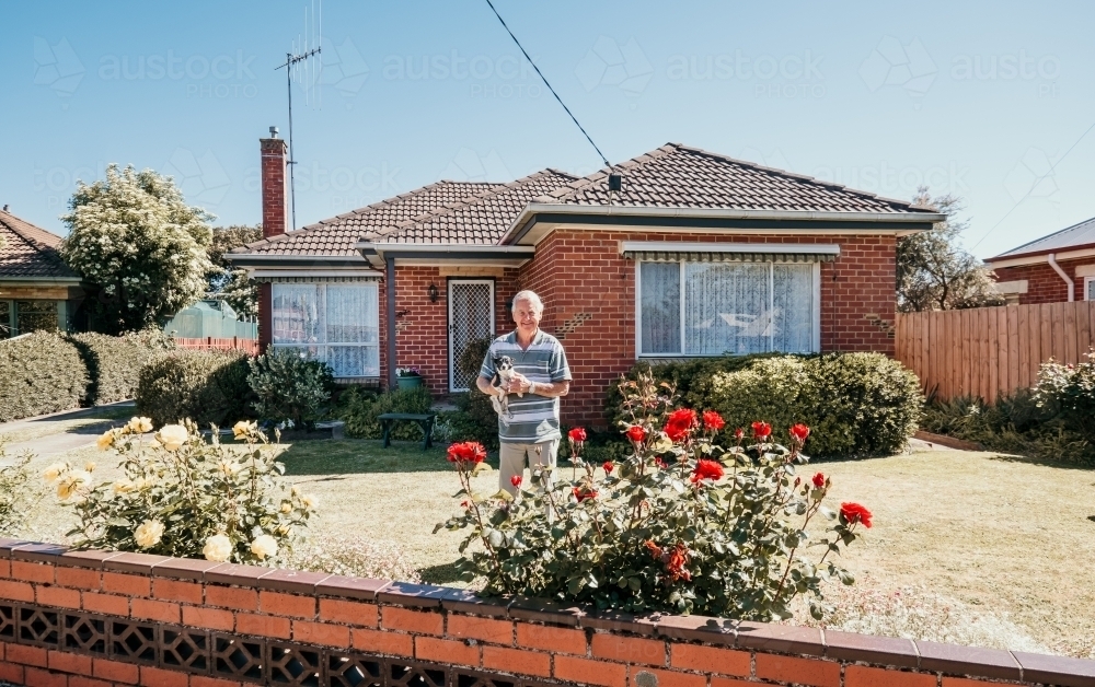 Elderly man and his dog in front of his red brick home. - Australian Stock Image