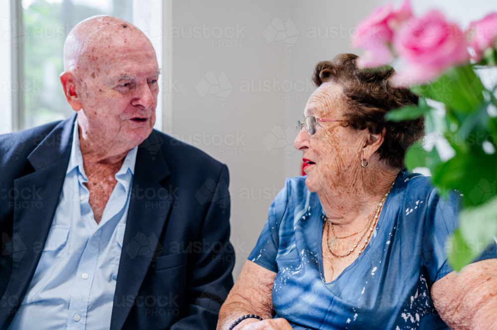 Elderly man and woman sharing a conversation while seated at the table - Australian Stock Image