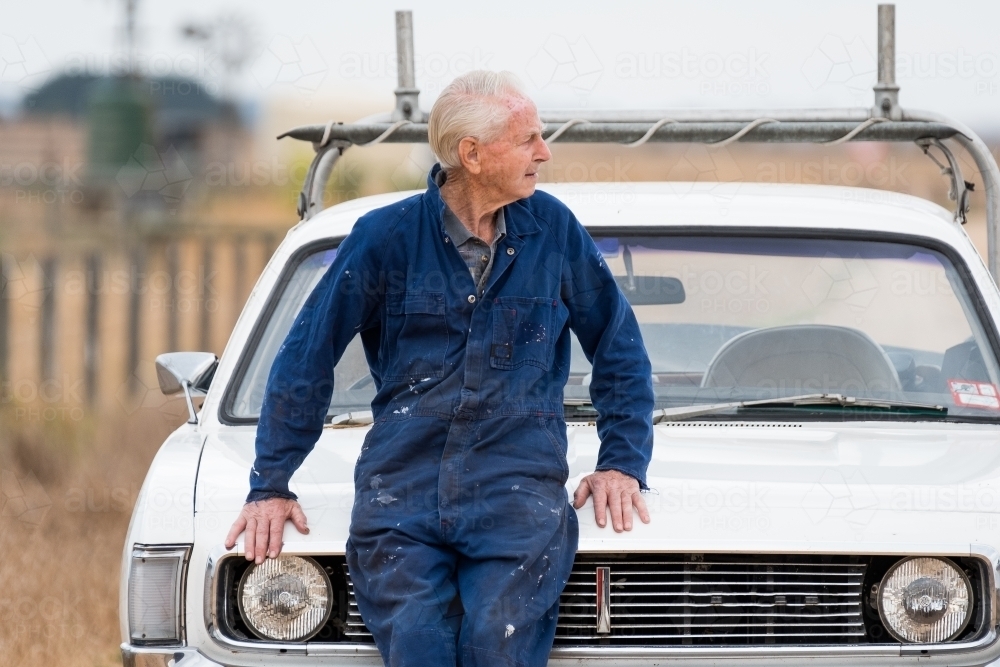 Elderly man leans against the bonnet of his car. - Australian Stock Image