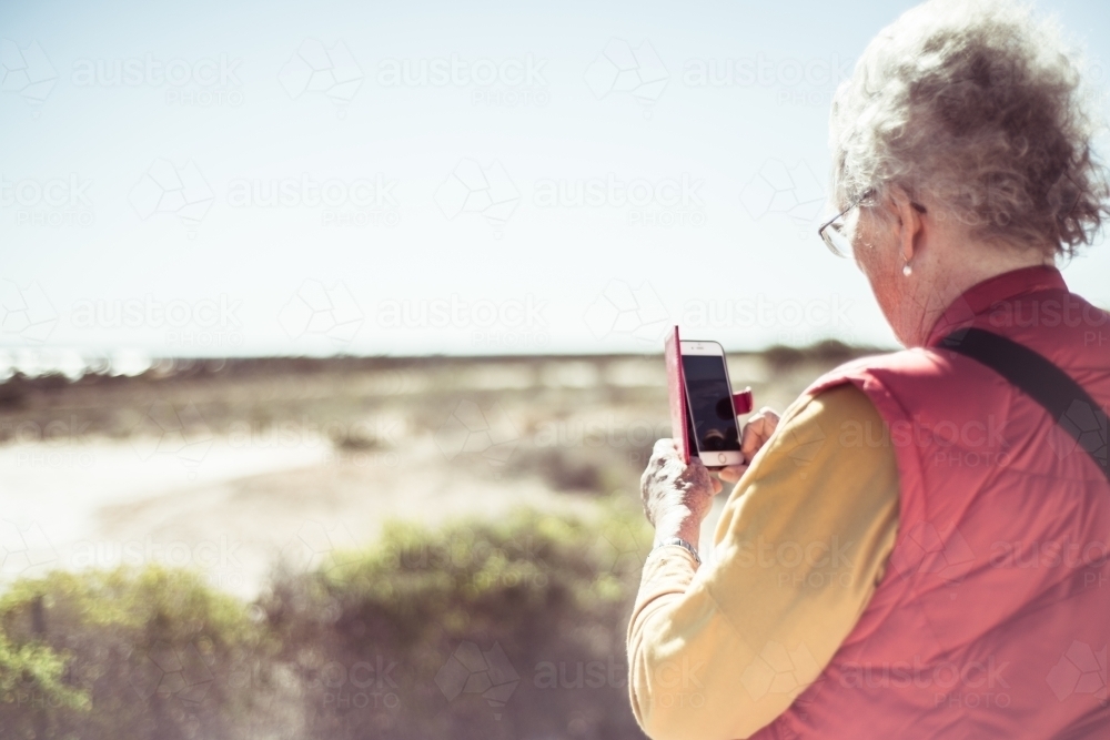 Elderly woman using phone to take photo - Australian Stock Image