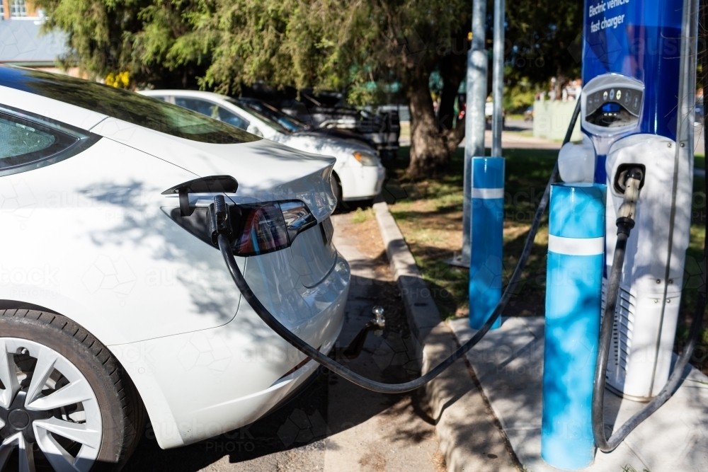 Image of Electric vehicle fast charger with EV car plugged in to charge