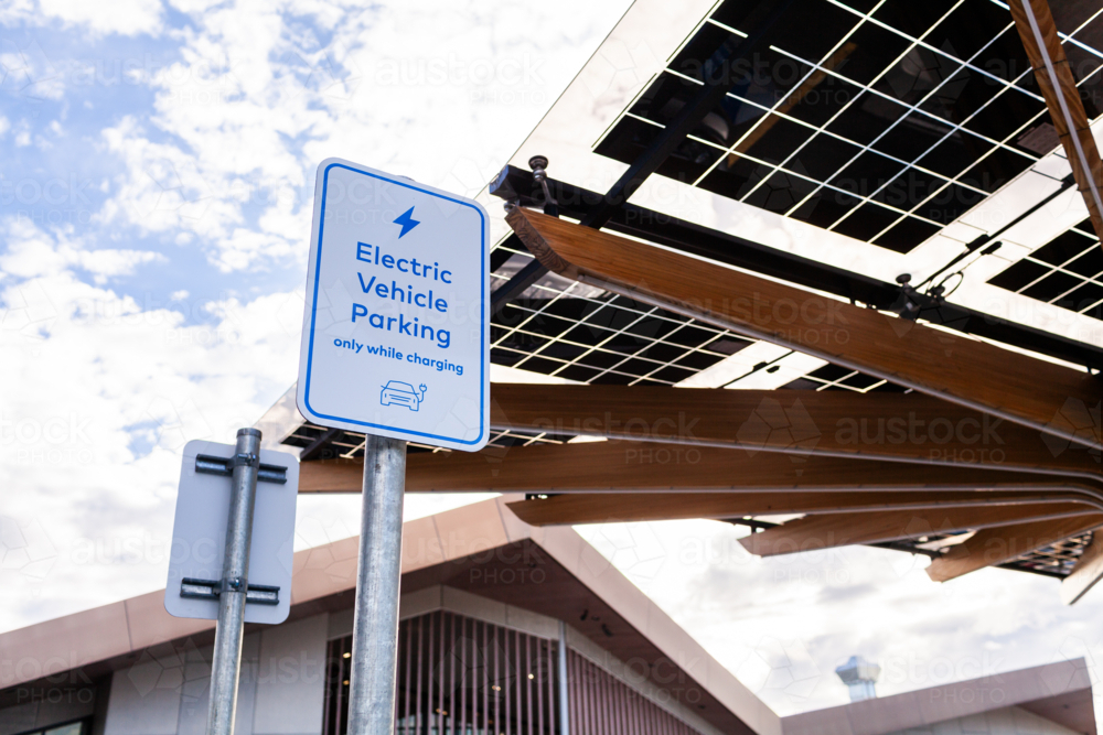 Electric Vehicle parking only while charging sign with solar panels above - Australian Stock Image