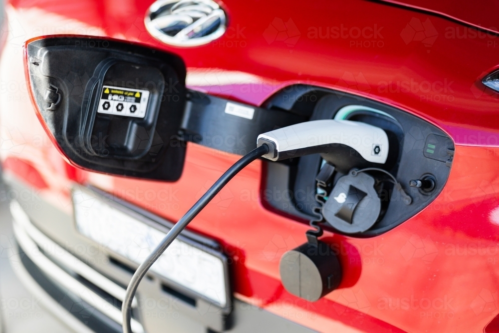 Image of electric vehicle with home charging cable plugged in to front ...