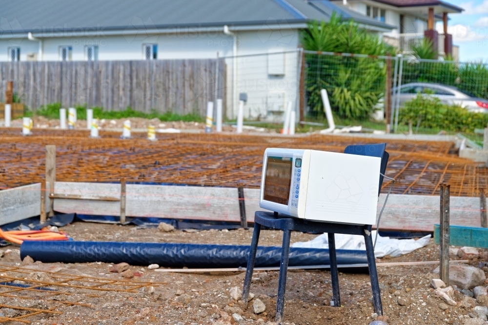 Electrical appliances exposed to the elements, on a chair at a new construction site - Australian Stock Image