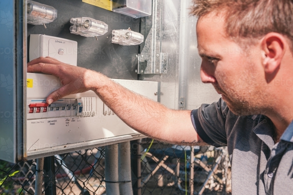 Electrician checking switches at the power box - Australian Stock Image