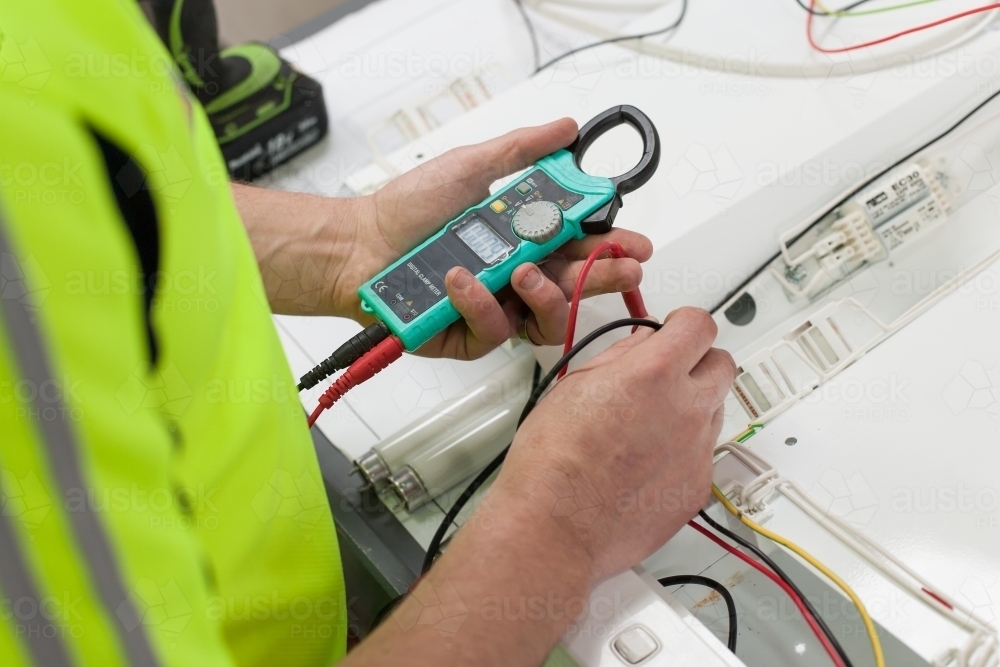 Electrician testing current with a multimeter - Australian Stock Image