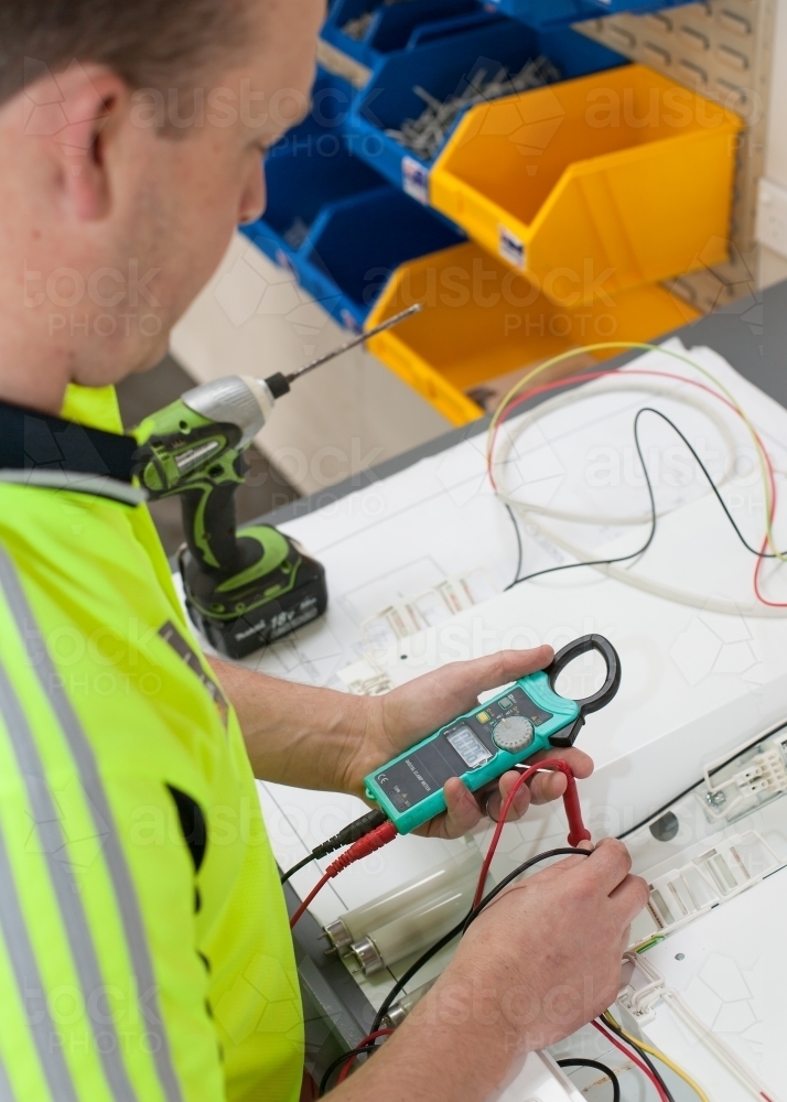 Electrician testing current with a multimeter - Australian Stock Image