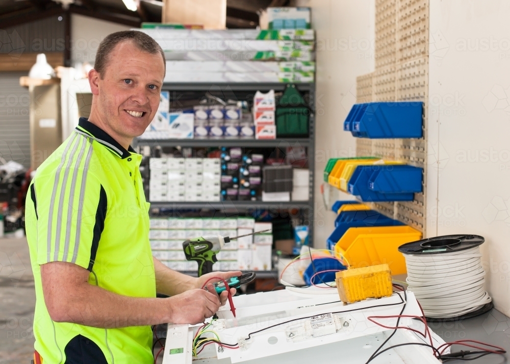 Electrician testing power board in his workshed - Australian Stock Image