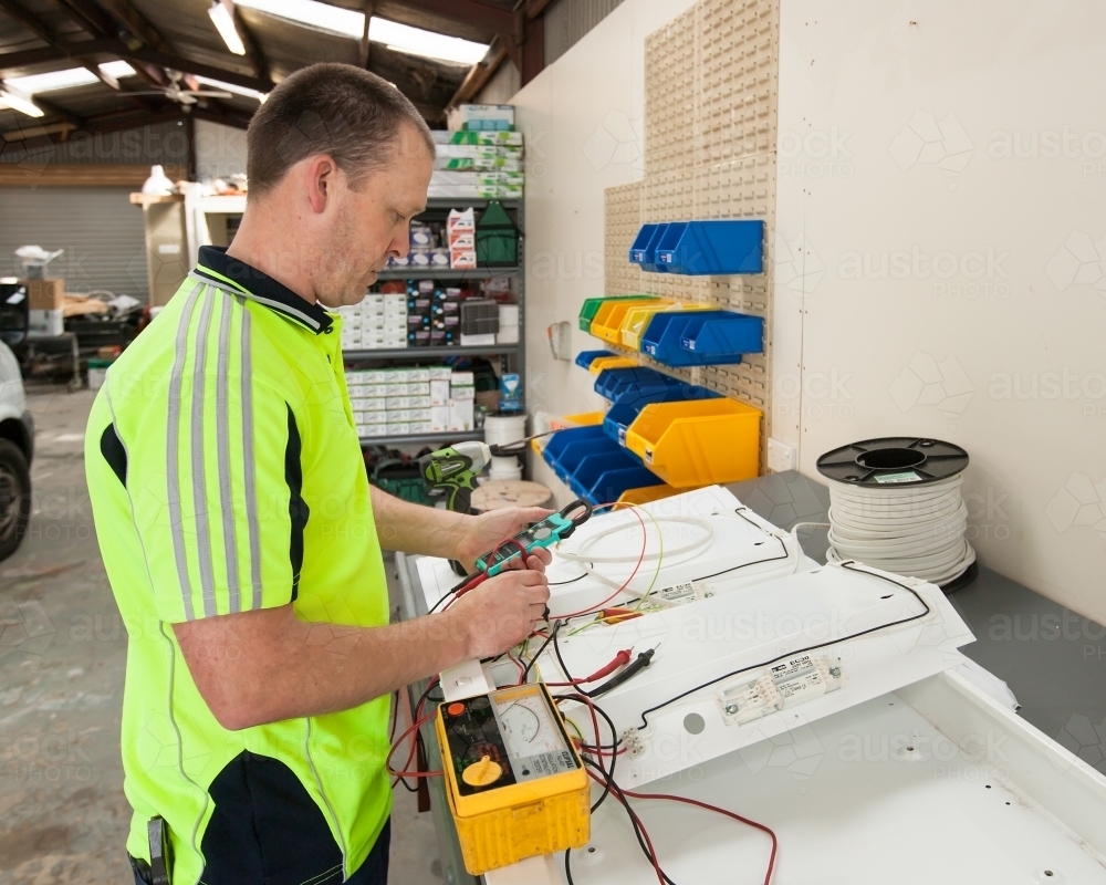 Electrician testing power board in workshed - Australian Stock Image