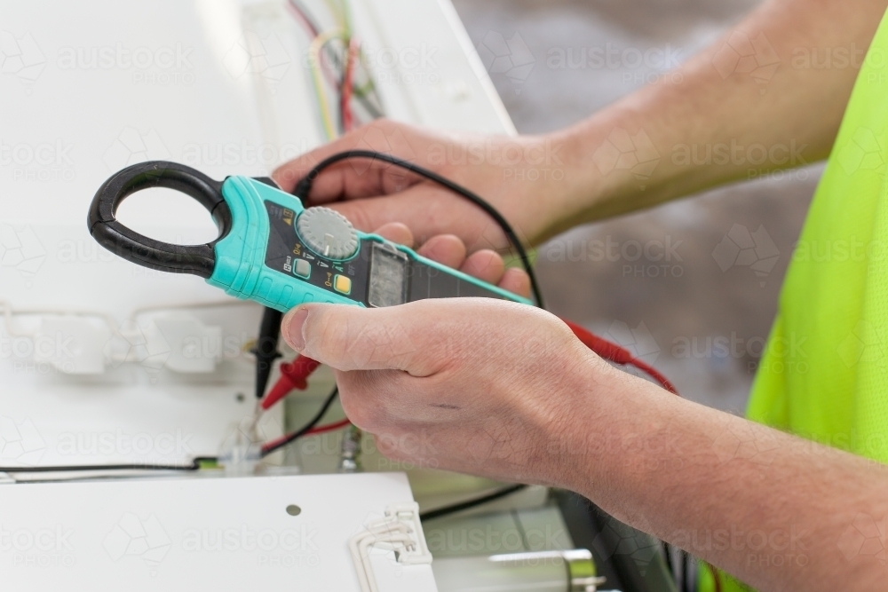 Electrician testing power board with a multimeter - Australian Stock Image